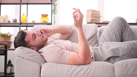 Man talking mobile phone, lying on sofa at home Stock Footage 171545887