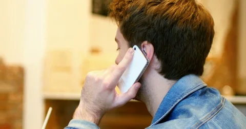 Man talking on mobile phone while drinking juice Stock Footage