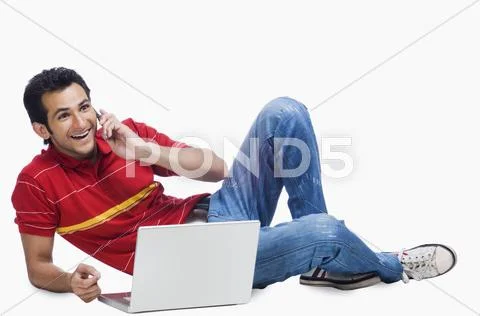 Man talking on a mobile phone while using a laptop Stock Photos