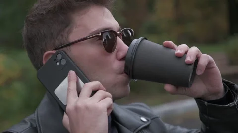 Man talking on the phone and drinking coffee Vidéo 219229458