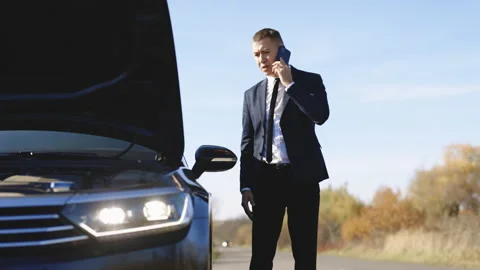 Man talking on the phone and looking at the car's engine. Young man use Stock Footage 194754226