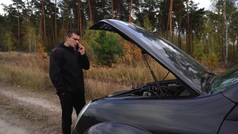 Man is talking on the phone around a broken down car. Stock Footage 141567704
