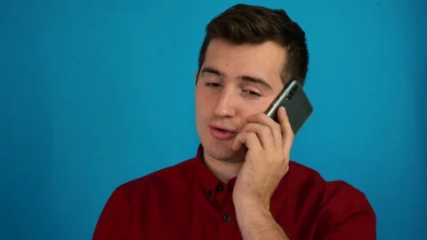 A man is talking on the phone on a blue background Stock Footage 142027931