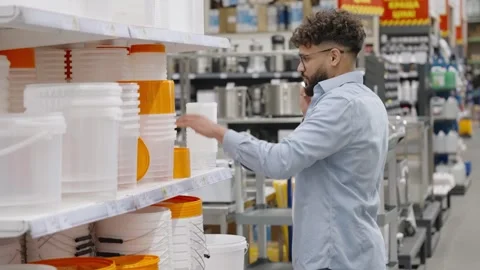 Man talking on phone choosing buckets in hardware store Stock-Footage 336965511