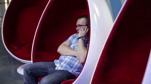Man talking on the phone in an egg-shaped chair Video stock 58200495