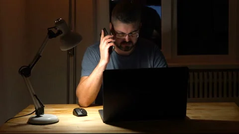 A man is talking on the phone. The lamp on the table is on 4K Stock-Footage 130149891