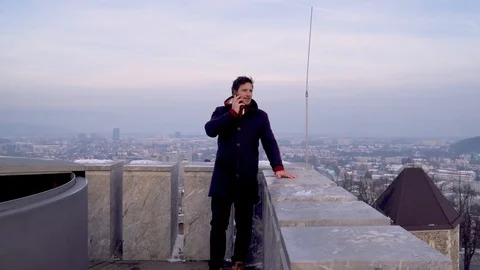 Man talking on a phone outside in winter time witha view of a city at background Stock Footage 101824855