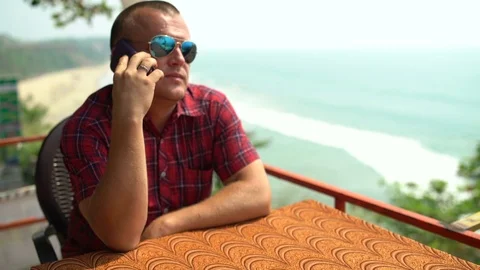 Man talking on the phone sitting in a cafe Stock Footage 74759036