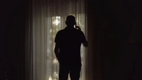 Man Talking On The Phone Standing At Window Front Overlooking The City Stock Footage 196735805