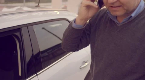 Man talking on the phone while charging its electric car Stock Footage 62226416