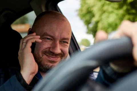 A man talking on the phone while driving a car. Stock Photos