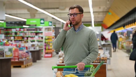 Man talking on phone while grocery shopping in supermarket Stock Footage 304088868