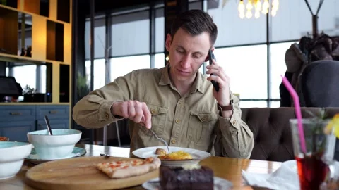 Man talking on phone while having lunch at restaurant Stock Footage 308439449