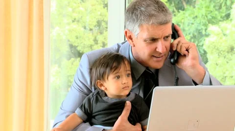 Man talking on phone while his baby is fidgeting on his lap 스톡 동영상 2872545