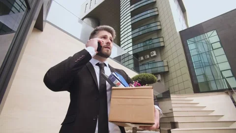 Man talking on the phone while leaving his workplace after dismissal Stock Footage 307188689