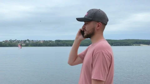 Man talking phone while standing near wide lake in slow motion Stock Footage 91726177