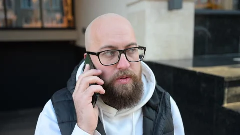 Man talking on phone while standing outside modern building during daytime Stock Footage 346769701