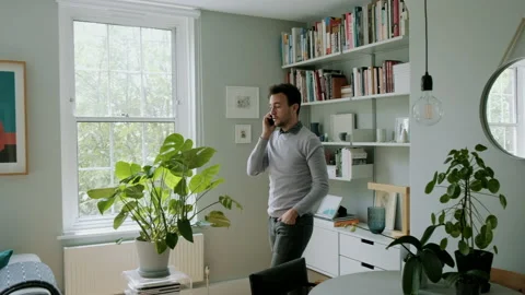 Man talking on phone while walking across living room Video stock 130606143