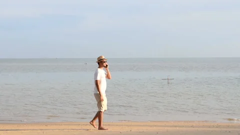 Man talking on the phone while walking on the beach Video stock 145186429