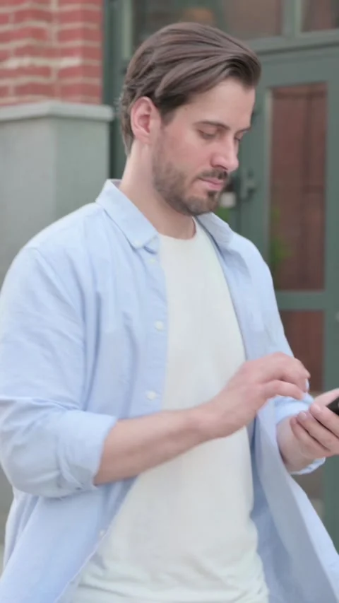 Man Talking on Phone while Walking in Street, Vertical Video Stock Footage 339665211