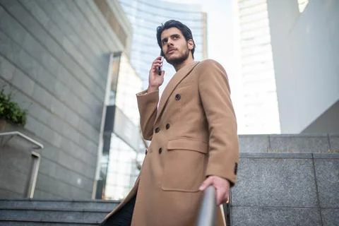 Man talking on the phone while walking down a stair Stock Photos