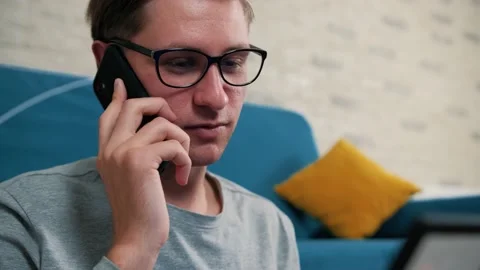 Man talking on phone while is working on laptop, sitting on bean bag at home. Stock Footage 146901521
