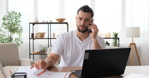 Man talking on the phone while working with a laptop at home on quarantine Stock Footage 150021585