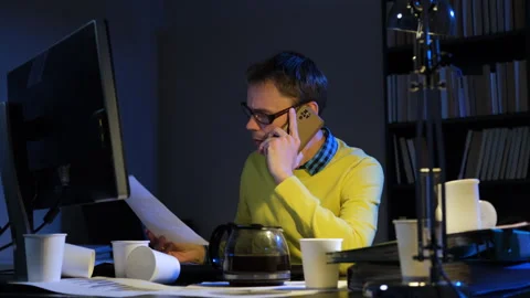 Man talking on phone while working late in office Vídeos de archivo 244945044