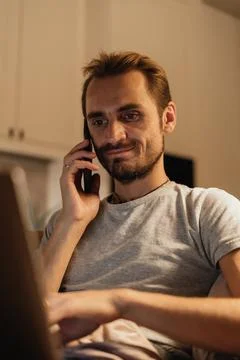 Man Talking on the Phone While Working on a Laptop, Expressing Connection a.. Stock Photos