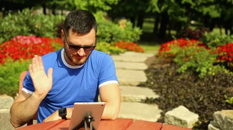 Man is talking on the Skype in the park Stock Footage 65819696
