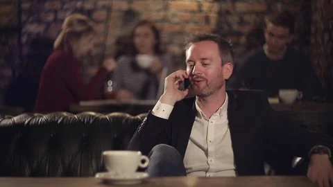 Man talking on smart phone on cafe and drinking coffee Video stock 69844537