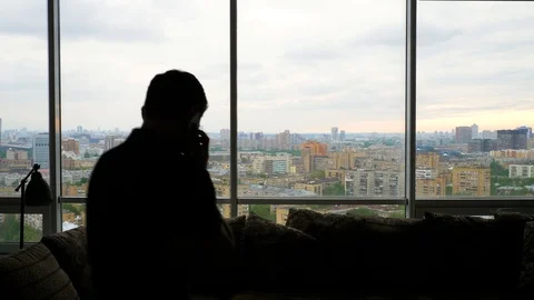 Man talking on the smartphone enters frame and exits near the panoramic window Stock Footage 103199692