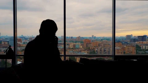 Man talking on the smartphone enters frame and exits near the panoramic window Stock Footage 103199731