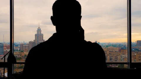 Man talking on the smartphone enters frame and exits near the panoramic window Stock Footage 103199953