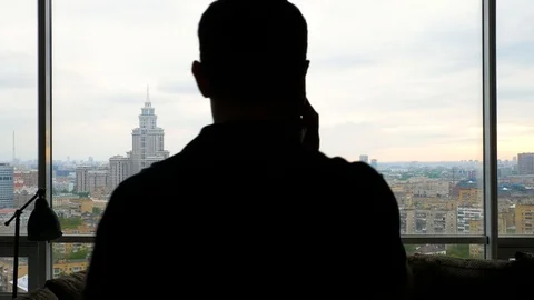 Man talking on the smartphone enters frame and exits near the panoramic window Stock Footage 103200133
