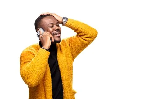 Man talking on smartphone with expressive emotion, wearing a warm yellow Stock Photos