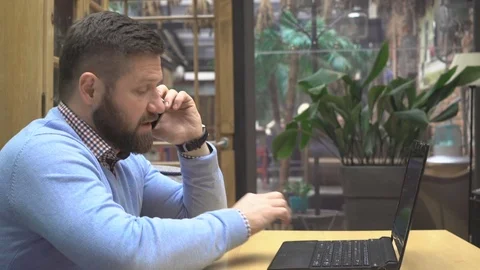Man talking by smartphone, finish working on laptop computer, in pub, steadicam Vídeos de archivo 73072758