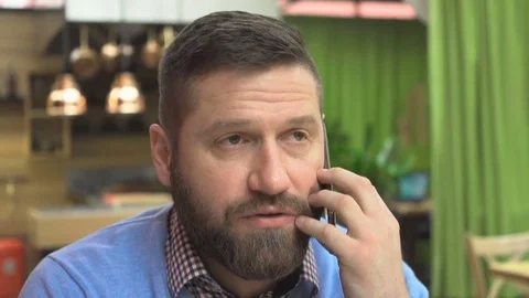 Man talking by smartphone, looking at camera, portrait, in cafe, close steadicam Vídeo Stock 73067337