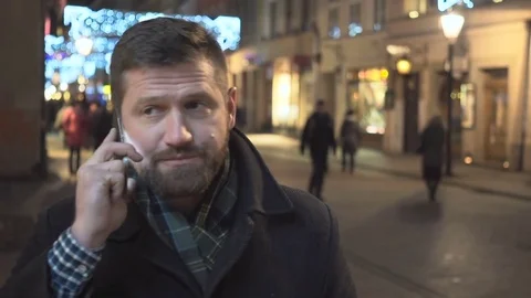 Man talking by smartphone, smiling at camera, night, Christmas, close steadycam 库存影片 72781884
