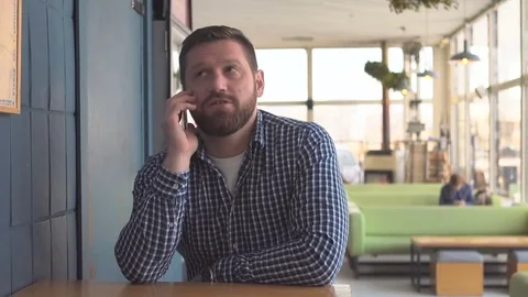 Man talking by smartphone, smiling at camera, portrait, cafe, steadycam shot  Vidéo 72951032