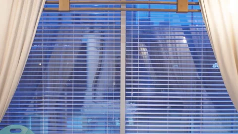 Man talking on a smartphone standing at the panoramic window with an evening Stock Footage 112048398