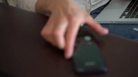 Man talking on smartphone while sitting on couch with laptop, working remotely Stock Footage 154796397