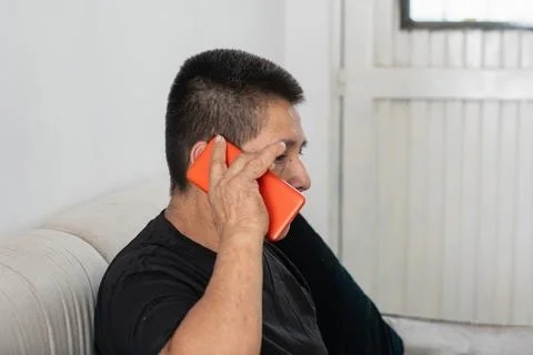 Man talking on smartphone while sitting on couch showing communication in e.. Stockfoto's