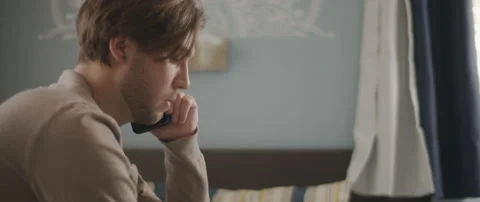 A man talking to someone on the phone while working with a laptop from home. Stock Footage 135096164