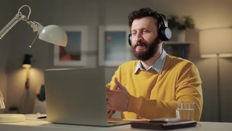 Man is talking on video call. Friendly smiling bearded man in headphones sitting 動画素材 171306784