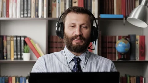 Man talking video connection and swears. Working bearded man in headphones at Stockbeeldmateriaal 133494635