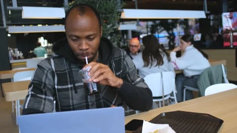 Man talking via video link on laptop while sitting at food court Video stock 234551226