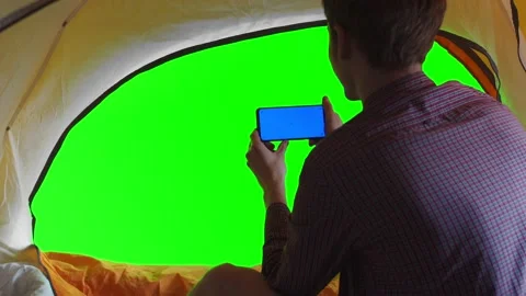 Man is talking via video link in tent, back view. Phone is located horizontally Stock Footage 219264846