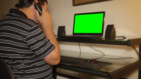 MAN TALKING ON A WIRELESS PHONE in front of computer Stock Footage 53228142