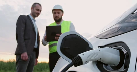 Man talks to engineer showing tablet near electromobile Видео